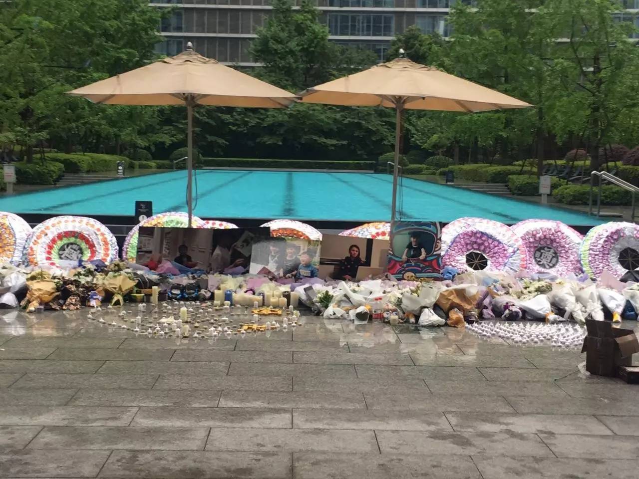 火災后，小區(qū)業(yè)主自發(fā)組織悼唁活動，草坪上逝者照片前擺滿了花圈、花束、蠟燭。（新京報記者王婧祎攝）