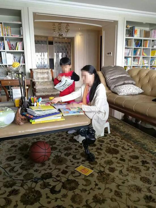 朱小貞和小兒子在客廳里，背后書架為起火點。（受訪者供圖）